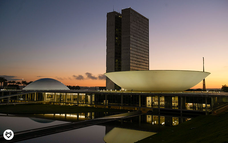 Imagem do Congresso Nacional sob a luz do pôr do sol. 