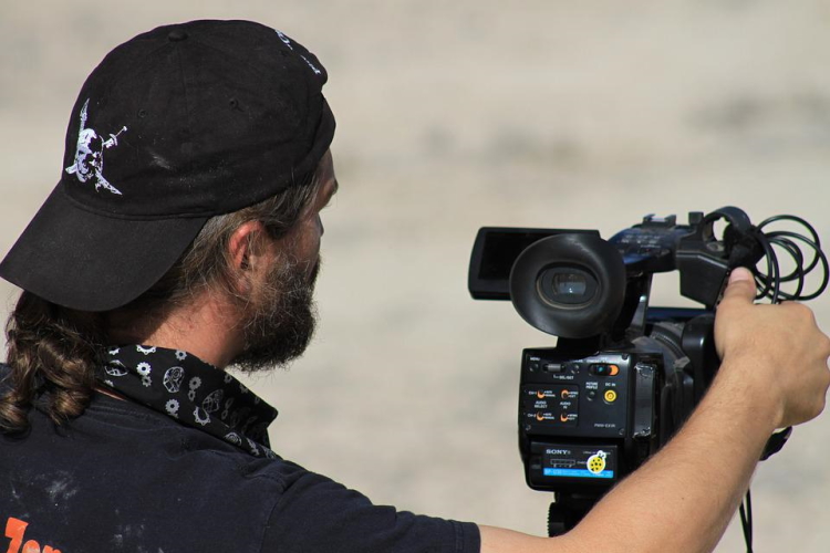 Imagem mostra homem operando câmera profissional de gravação de conteúdo político em vídeo.