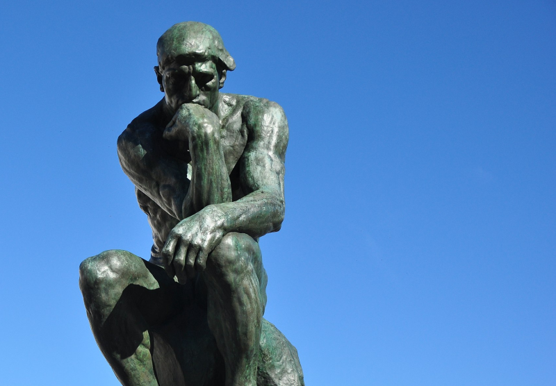 Fotografia mostra sobre fundo de céu azul a estátua do Pensador, de Auguste Rodin, simbolizando o pensamento e remetendo aos gatilhos mentais.