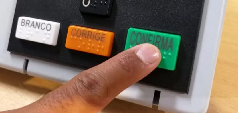 Fotografia tirada por Heloise Hamada, do portal G1, mostra dedo de eleitor apertando a tecla confirma na urna eletrônica. É o resultado de quem busca conquistar votos!