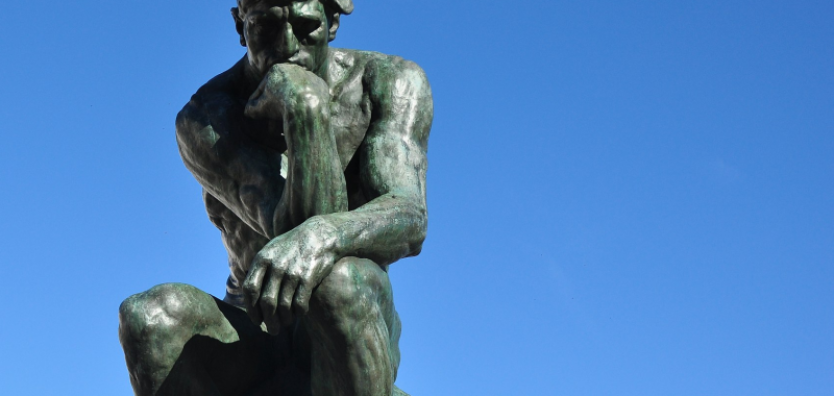 Fotografia mostra sobre fundo de céu azul a estátua do Pensador, de Auguste Rodin, simbolizando o pensamento e remetendo aos gatilhos mentais.